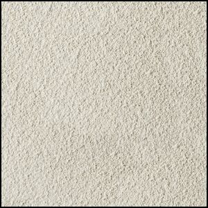 A close-up view of a textured, light beige, sandy surface with fine, granular particles evenly spread across the image.