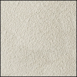 A close-up view of a textured, light beige, sandy surface with fine, granular particles evenly spread across the image.