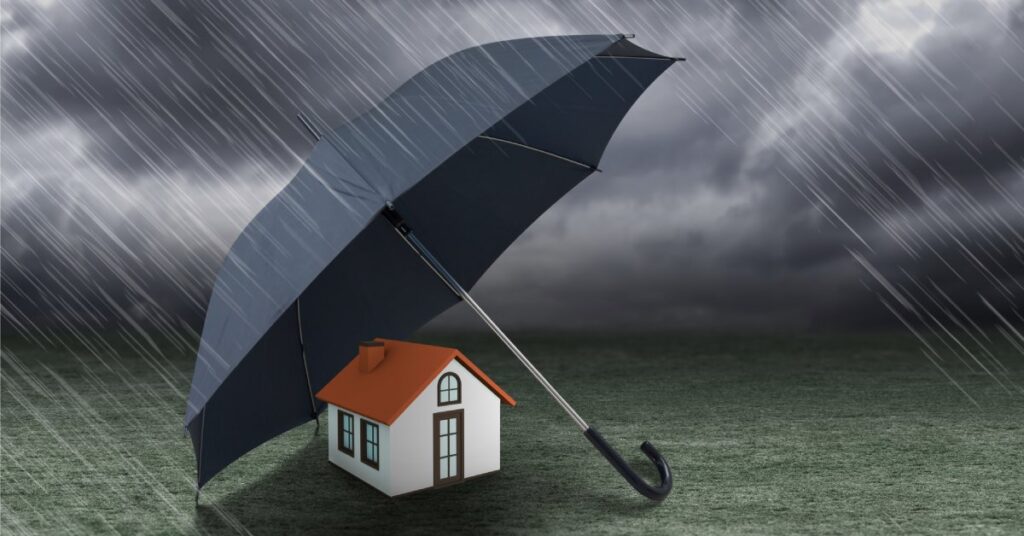 A cartoon rendering of a large black umbrella blocking the rain from hitting a small white house with an orange roof.