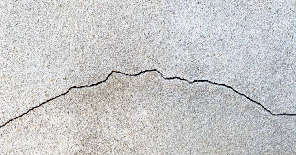 A close-up view of a large crack on a cement wall. The jagged crack runs the whole way from left to right.